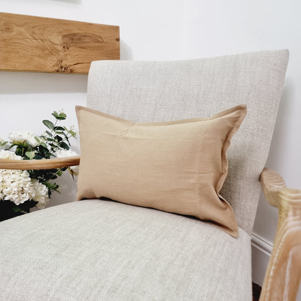 rectangle beige brown cushion sat on a cream armchair.
