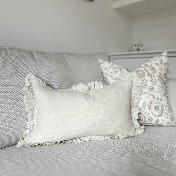 sand coloured ruffled edge rectangle cushion sat on a cream sofa