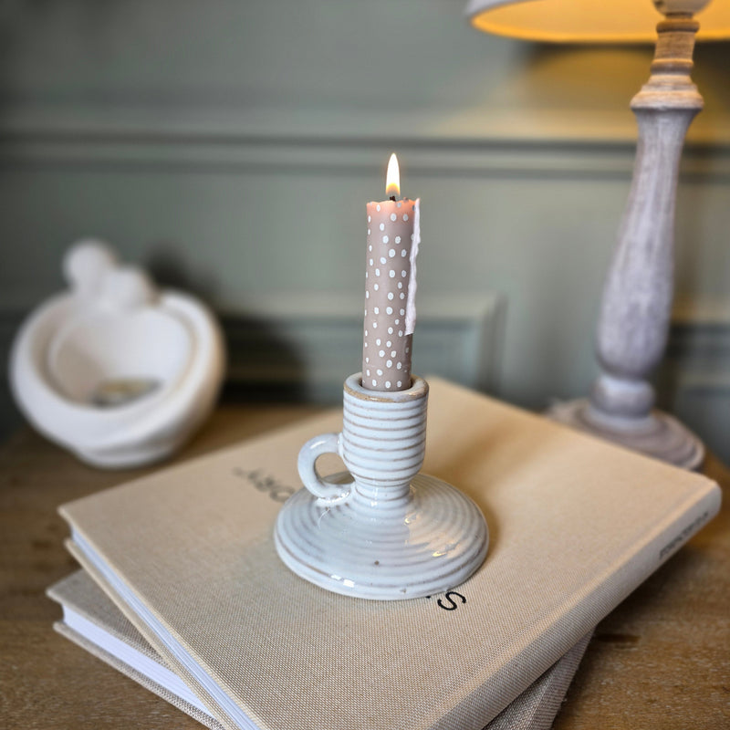 Ceramic Taper Candle Holder with Handle sat on a book on a wooden bedside table