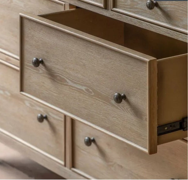 close up of the drawer of the oak bobbin 7 drawer chest. showing the lime wash and natural wood grain. 2 Bronzed round handles and drawer runners.