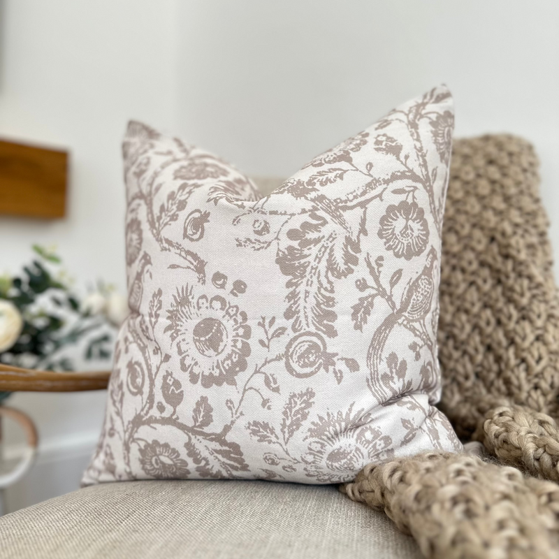 Cream and Brown country print square cotton cushion, sat on a cream linen armchair in a living room with a brown throw.