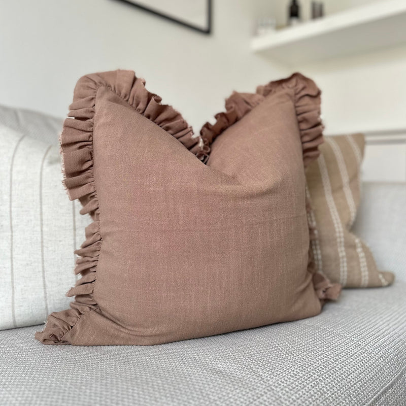 square brown cushion with a ruffled edge sat on a cream sofa