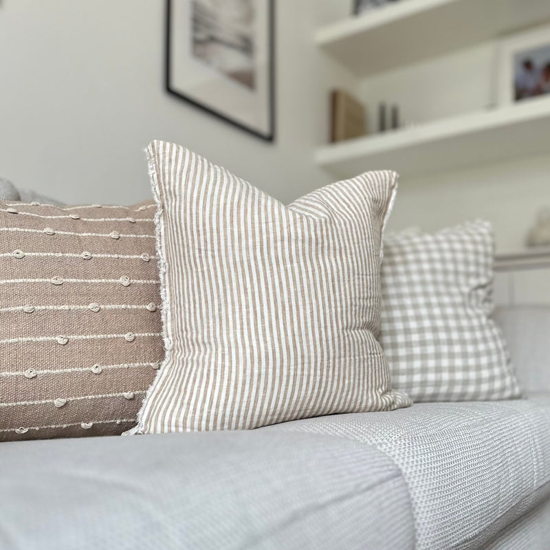 Weathered edge square cream cushion with a vertical beige stripe.