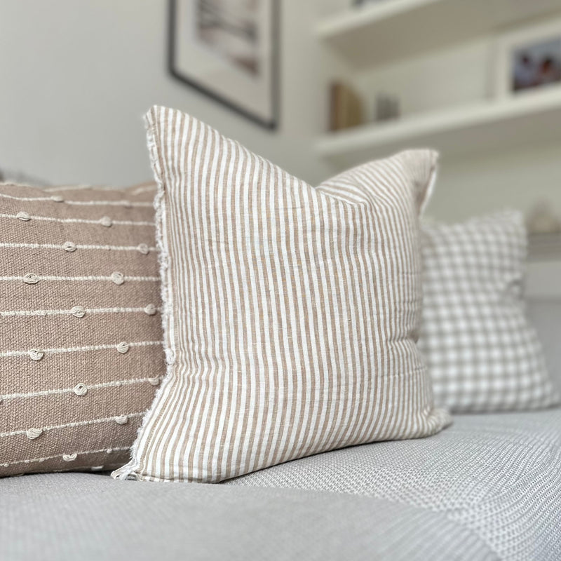 Weathered edge square cream cushion with a vertical beige stripe.