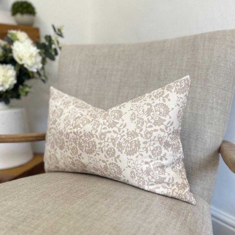 rectangle cream cushion with a beuatiful beige floral pattern all over. Sat on a cream armchair