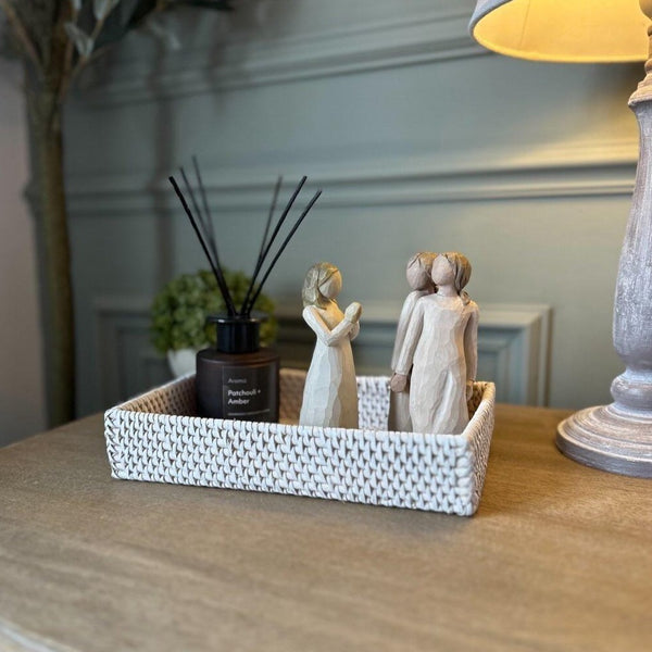 Small rectangle whitewash rattan tray, styled with a reed diffuser and ornamental figures all sat on a wooden bedside table
