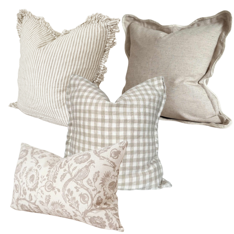 A set of 4 beige and cream country inspired print cushions. 1 Square cream ruffled edge linen cushion with a vertical all over beige stripe. 1 square greige cotton cushion with a cream scalloped edge. 1 x weathered edge linen cushion with a cream and beige gingham pattern and 1 rectangle cotton cushion with cream background and a large brown flower and pheasant print. All on a plain white background