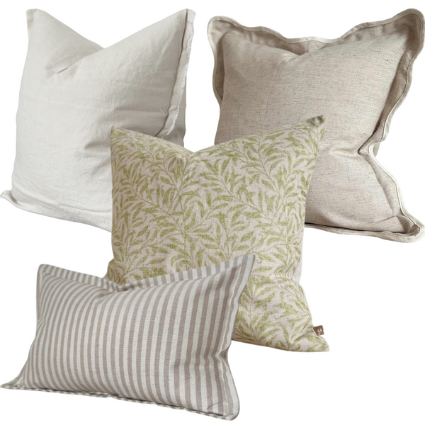 A set of 4 cushions. 1 Weathered edge square linen cream cushion, 1 cotton square greige cushion with a cream piping around a scalloped edge. 1 cotton beige cushion with a botanical green leaf print. 1 cotton rectangle cushion with a flanged edge and a cream and beige vertical chunky stripe. All filled with our luxury duck feathered filled pads