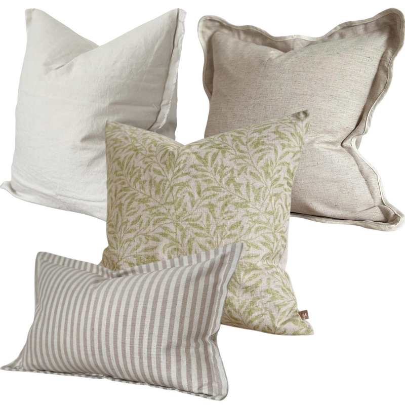 A set of 4 cushions. 1 Weathered edge square linen cream cushion, 1 cotton square greige cushion with a cream piping around a scalloped edge. 1 cotton beige cushion with a botanical green leaf print. 1 cotton rectangle cushion with a flanged edge and a cream and beige vertical chunky stripe. All filled with our luxury duck feathered filled pads