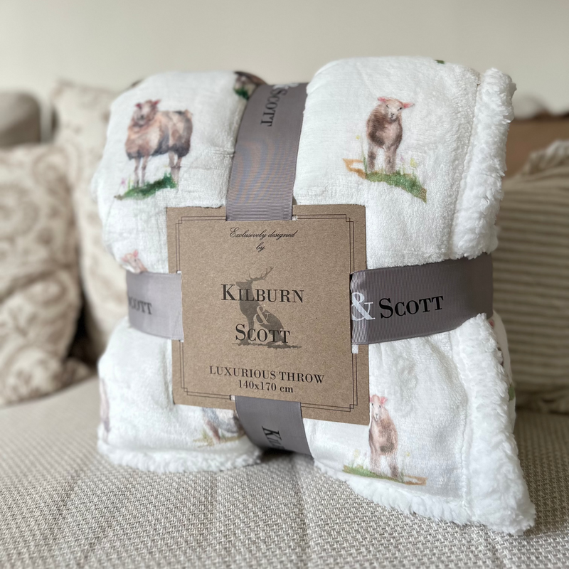 Soft, fluffy white sherpa blanket with an all over white sheep print. Sat on a cream sofa