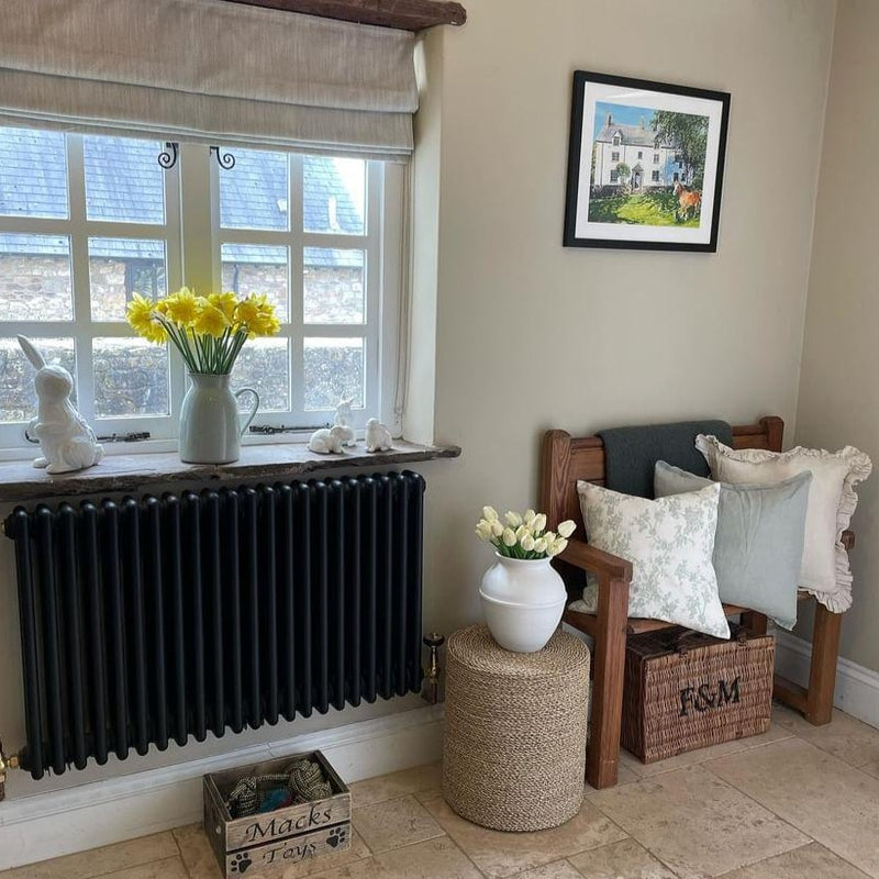 Weathered edge sage green cushion sat on a pew in a farmhouse kitchen with a cream cushion and a cream and sage floral pattern cushion to compliment the look 