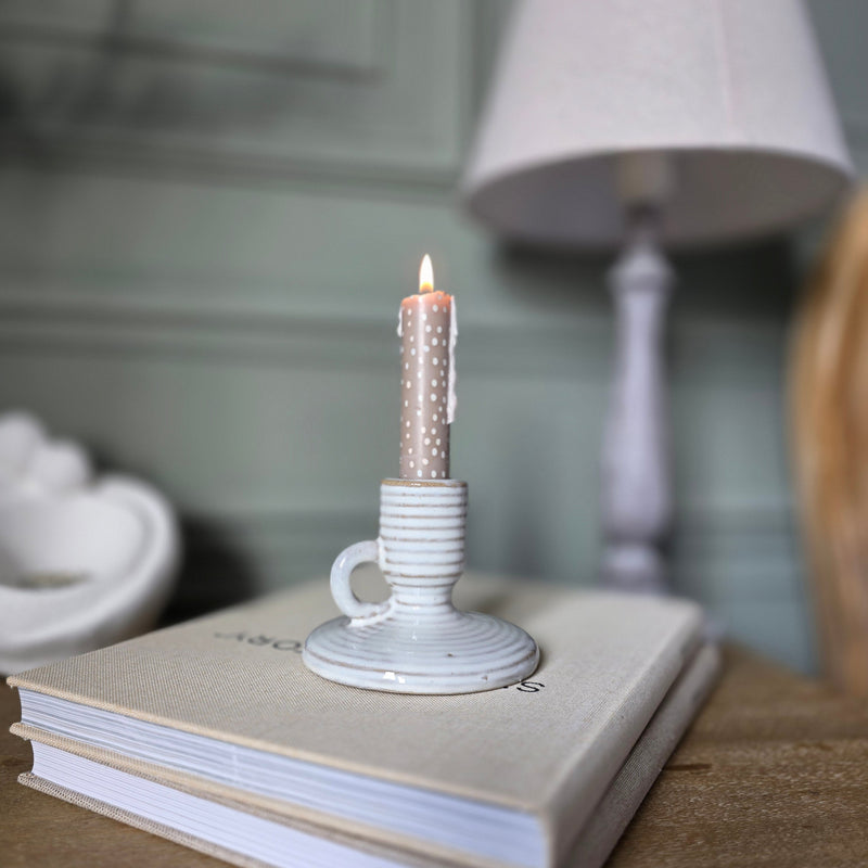 small ceramic candle stick holder sat on a bedside table