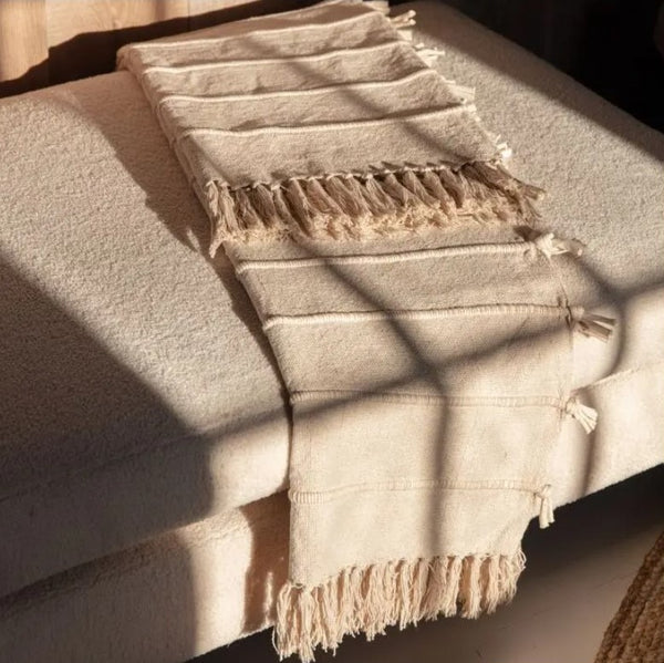 Cream throw with cream tassels laid on a cream sofa