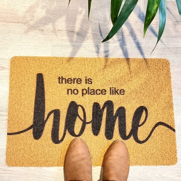 Light brown doormat with dark brown there is no place like home printed on