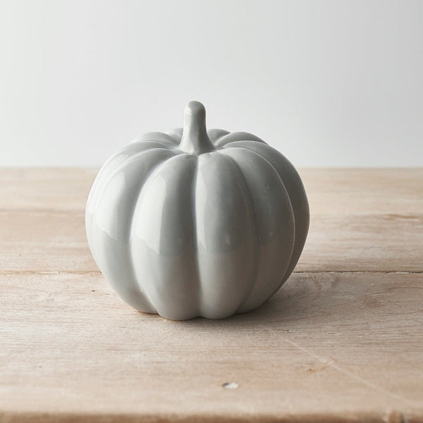 Grey ceramic pumpkin ornament sat on wooden sideboard 