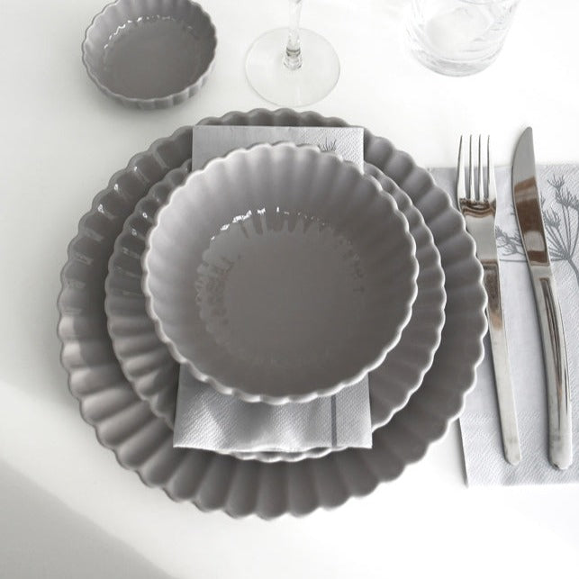 Grey floral ceramic bowls with a scalloped edge and a matt finish. These bowls feature a beautiful floral shape and a glazed top, adding an elegant touch to any table setting. Available in small and large sizes, these bowls are perfect for serving various dishes.