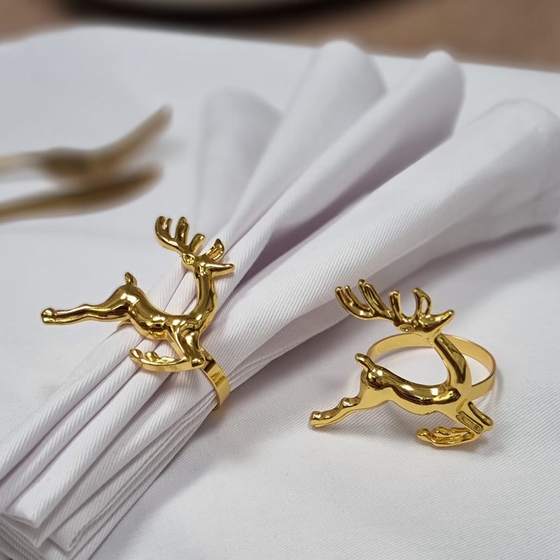 Two gold reindeer napkin rings on Christmas dining table