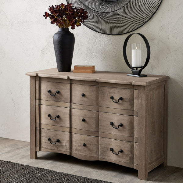 Cotswold Collection 3 Drawer Wooden Chest. Each drawer has 2 black handles. Sat in a living room displaying a black vase on top.
