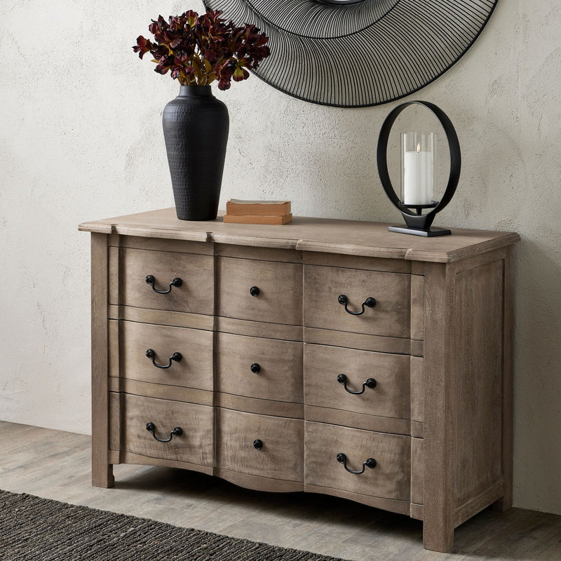 Cotswold Collection 3 Drawer Wooden Chest. Each drawer has 2 black handles. Sat in a living room displaying a black vase on top.