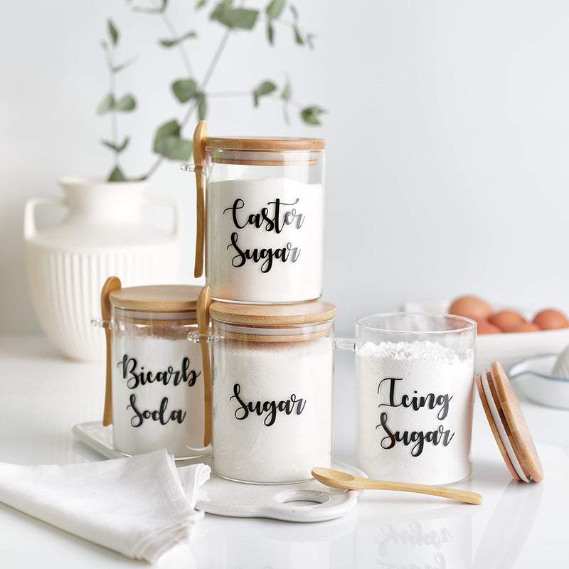 Four glass jars with wooden bamboo lid and spoon with personalised black wording for baking