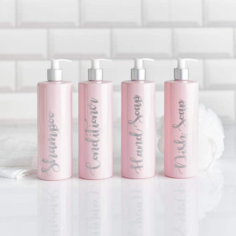 Four pink resubale bathroom dispenser bottles with shampoo conditioner hand soap and dish soap printed in silver wording